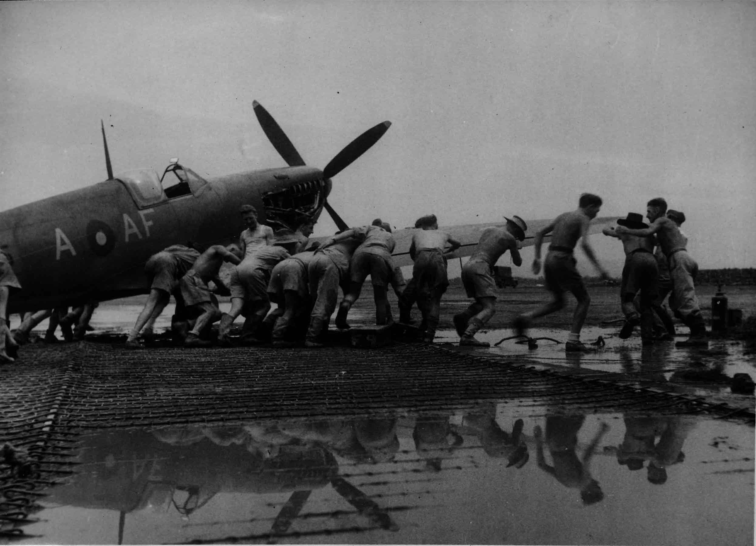 Manhandling a Supermarine Spitfire Mk VIII AF-A of No. 607 'County of Durham' Squadron through the monsoon mud at an advanced airfield on the Burmese border, 1944 (RAFM PC71/19/1742)