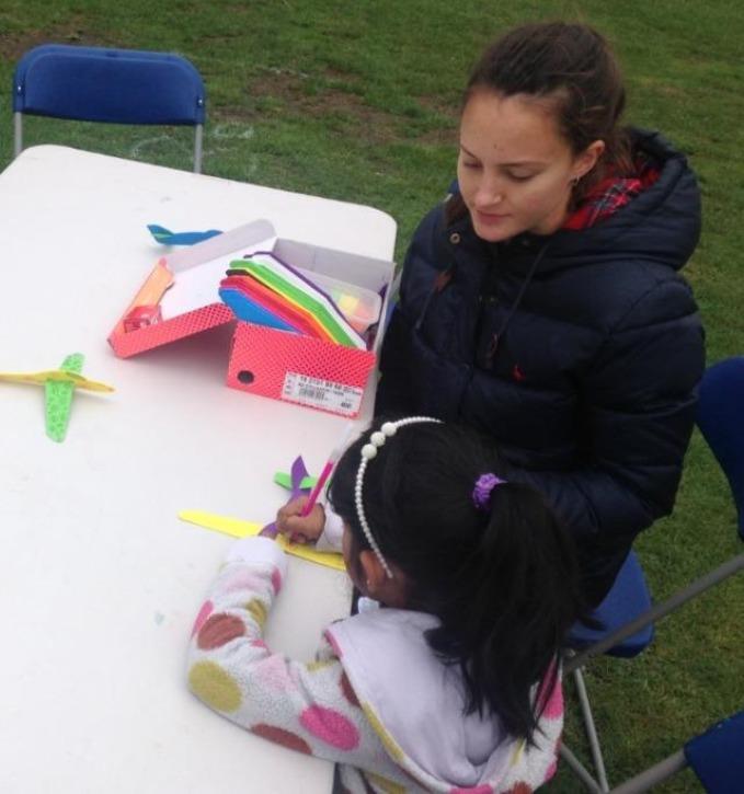 A Volunteer helping a girl make a foam plane