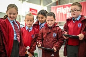 A group of children holding iPads and engaged in a stem Activity. The atmosphere is fun and cheerful.