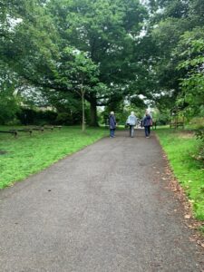 Four people in the distance walking along a paved pathway with grass and trees either side