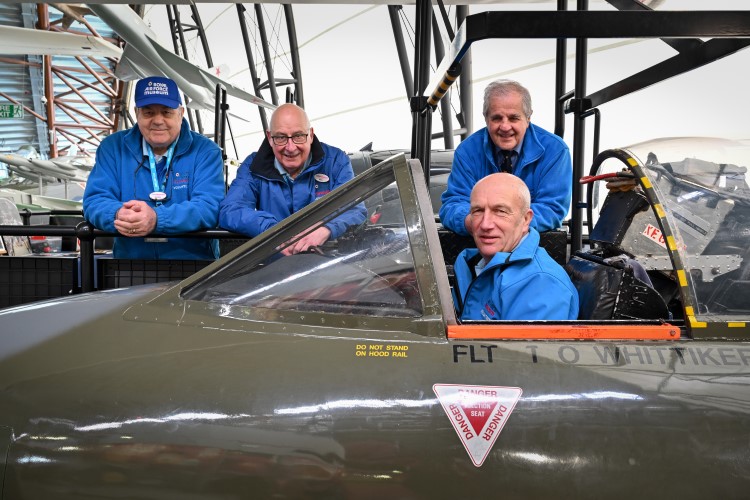 Volunteers smiling beside an aircraft cockpit.