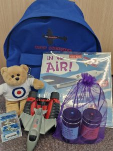 SEND Family Backpack showing the items inside - book; teddy; binoculars; smell pots; aeroplane; aqua cube