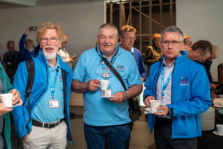 Volunteers smiling beside an aircraft cockpit.