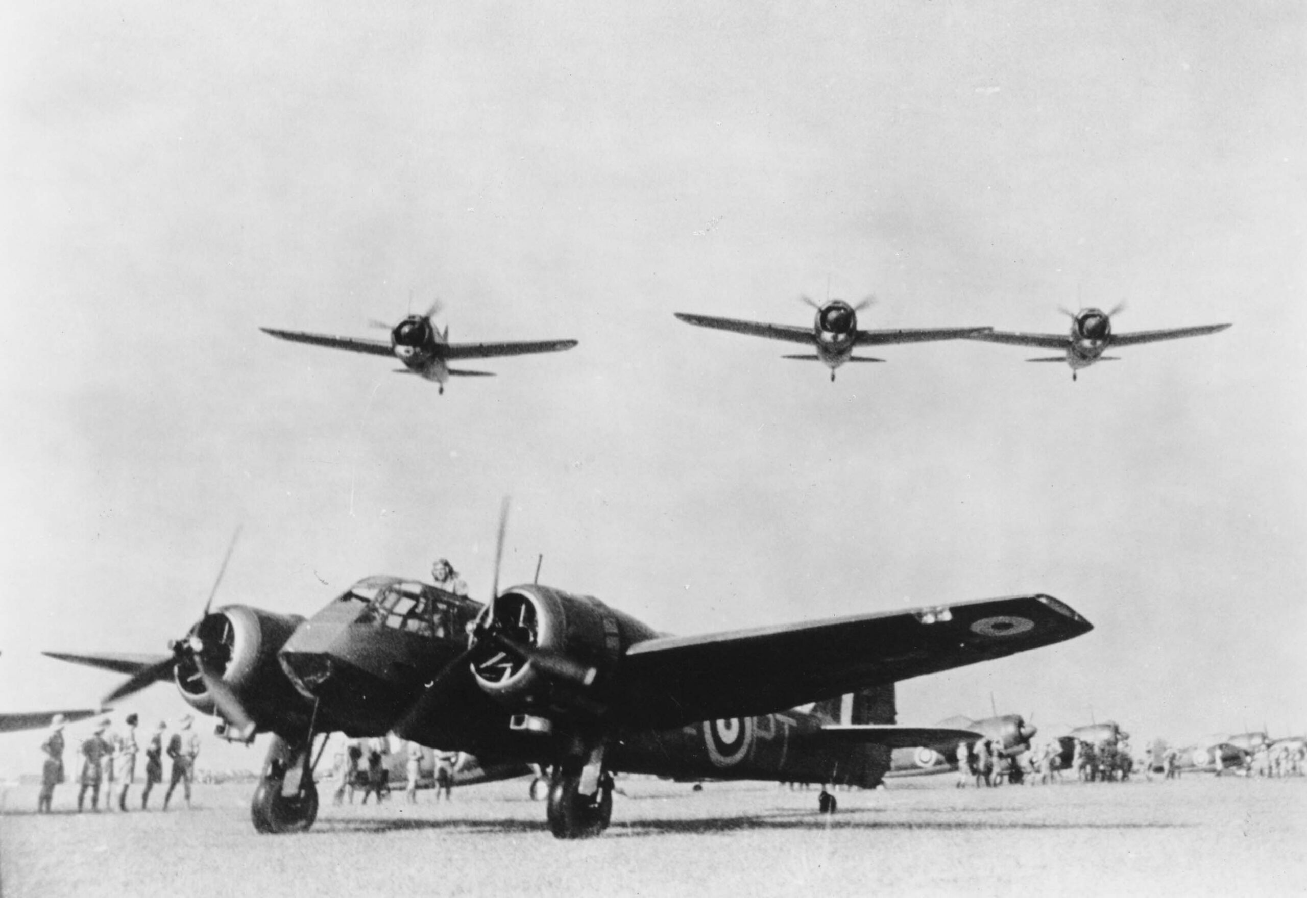 Three Brewster Buffalos fly over a No. 62 Squadron Bristol Blenheim at RAF Tengah, circa 1941 (RAFM X003-2674/1448)